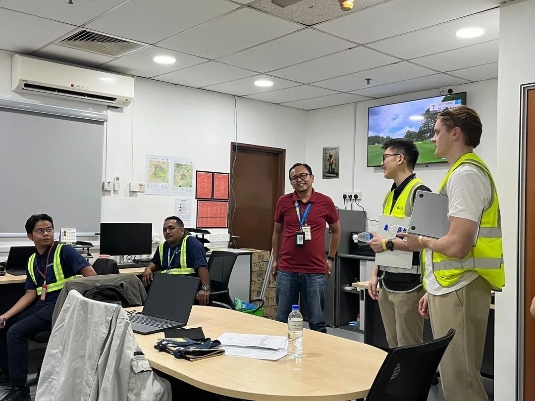 Two Belli team members presenting from laptops in a customer's operations office
